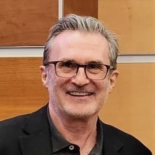 A smiling older white man wearing eyeglasses.