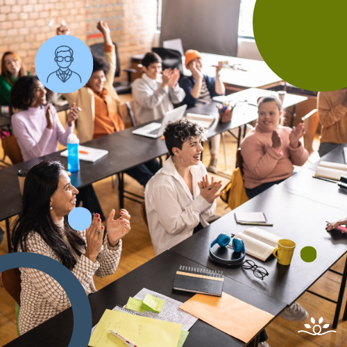 A lively classroom with students of various backgrounds seated at tables, clapping and smiling. The foreground features two women in conversation, one in a white blouse and another in a cream sweater. Bright daylight streams in through tall windows. Circular overlays in green and blue decorate the edges. Upper left shows a white faculty icon in a blue circle. NDCSS logo bottom right.