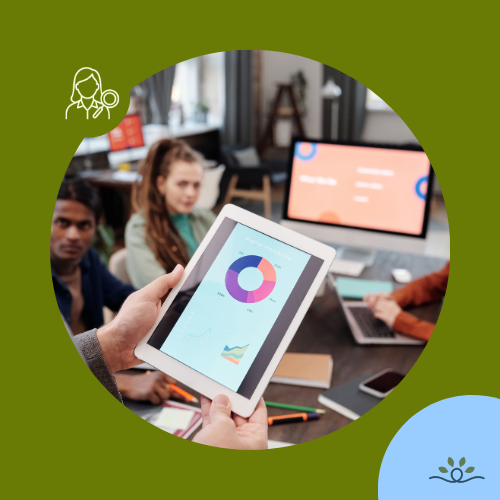 Close-up of a tablet being held in the foreground, displaying a colorful data visualization with a central purple-and-orange pie chart and smaller line graphs. In the blurred background, a group sits at a meeting table with laptops and a large monitor showing red and blue graphics. Circular crop over an olive-green background with a light-blue accent circle. Upper left contains a white researcher icon in a darker olive circle. NDCSS logo bottom right.