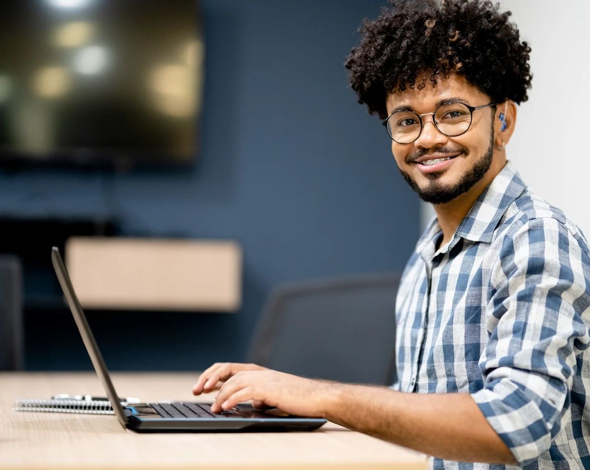 Smiling, college student working on a laptop at a desk